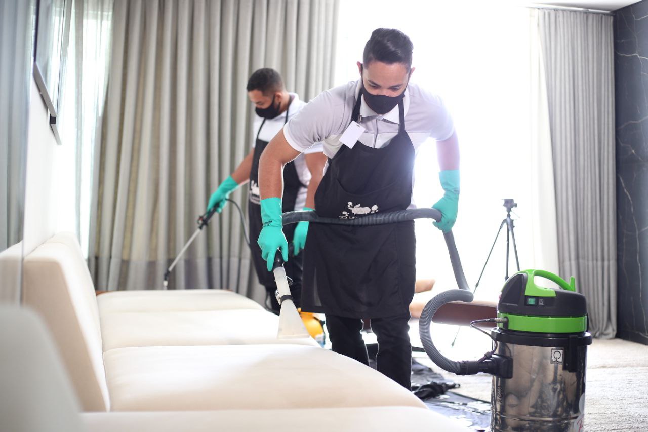 Dois profissionais higienizando um sofá com equipamentos de extração